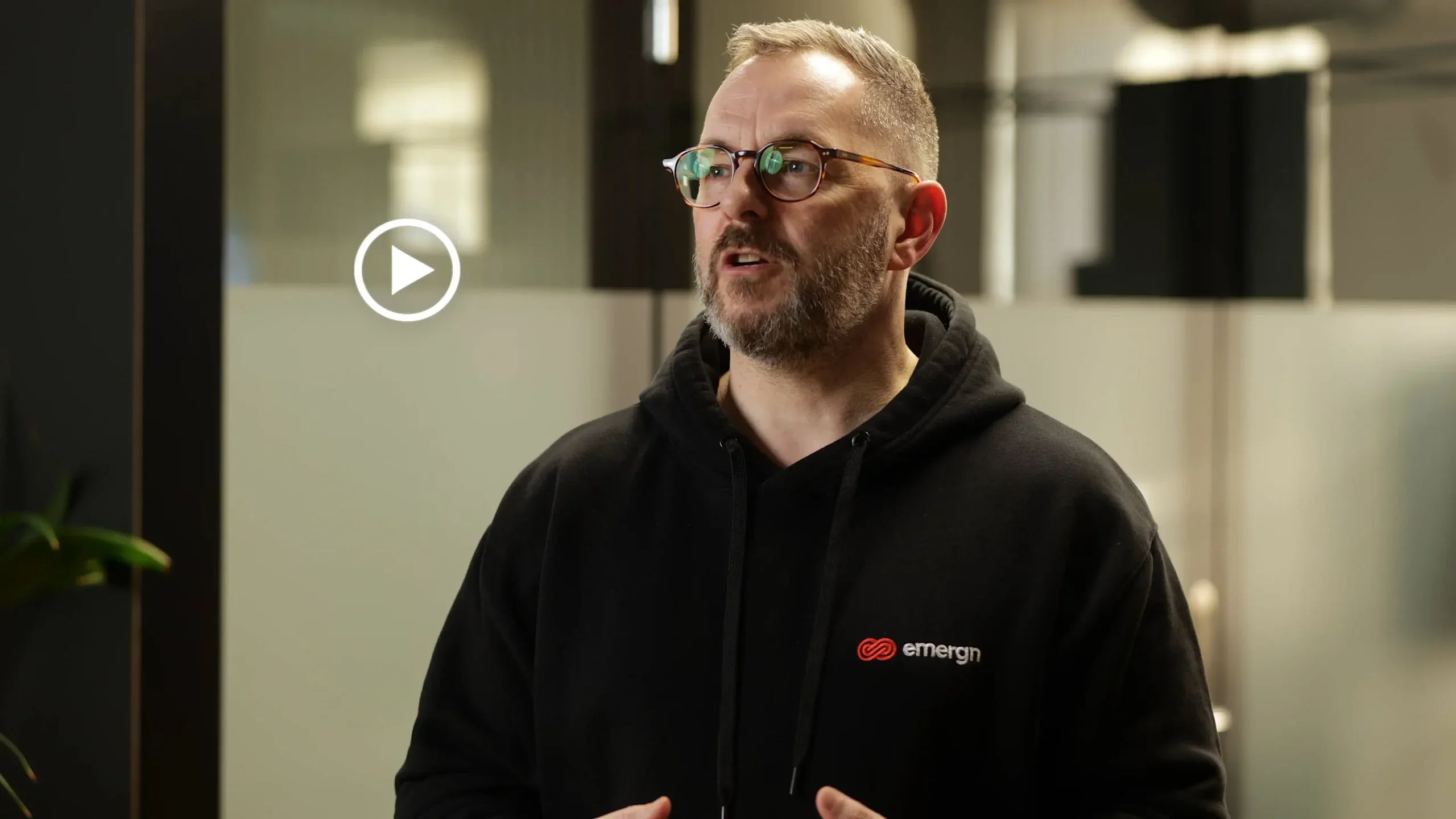 A person wearing a VR headset in a dark room lit with red and blue lights, smiling and reaching forward as if interacting with virtual objects.